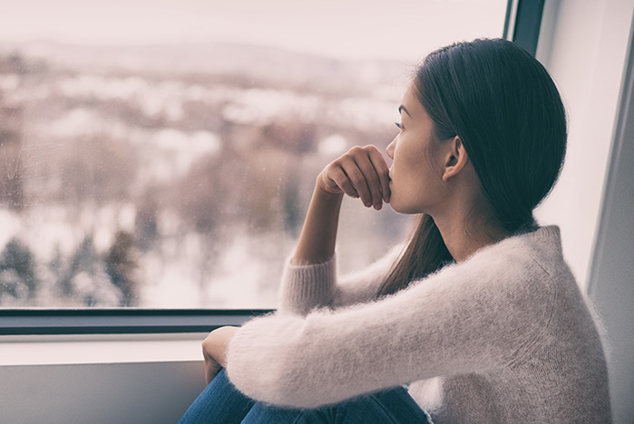 Sad woman contemplating while looking out window