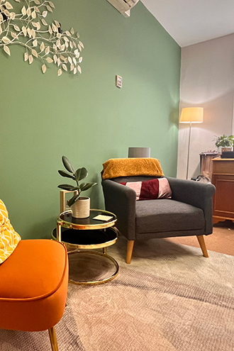 Cozy living room featuring a bright yellow sofa with decorative cushions, a small plant, and a stylish bookshelf, creating a welcoming atmosphere.