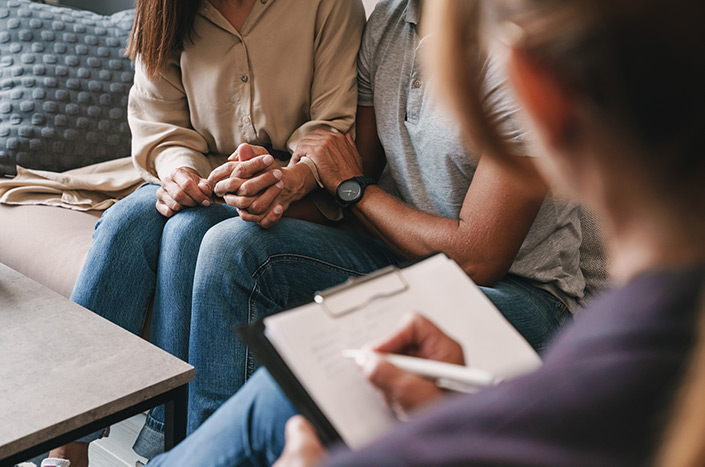 Man and woman attending couples therapy while holding hands