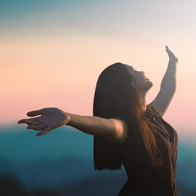 Happy woman with arms outstretched at sunset